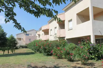 a row of apartment buildings with flowers in the yard at Chez Laurence et Fabien in Santa-Maria-Poggio