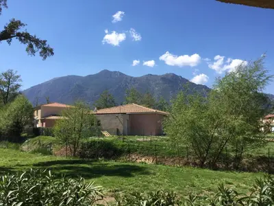 a house in a field with a mountain in the background at Chez Laurence et Fabien in Santa-Maria-Poggio
