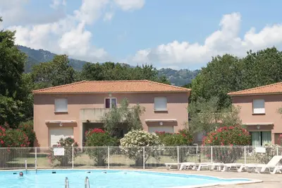 a hotel with a swimming pool in front of a building at Chez Laurence et Fabien in Santa-Maria-Poggio