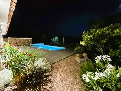 a garden with a swimming pool at night at Villa Nasya, 8 pers, piscine chauffée, 5 mn plage voiture in Gialla
