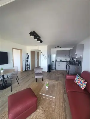 a living room with a red couch and a kitchen at Appartement dominant la baie d'Ajaccio in Ajaccio