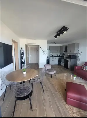 a living room with a table and chairs and a kitchen at Appartement dominant la baie d'Ajaccio in Ajaccio