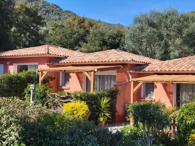 a red house with a mountain in the background at A VIGNA VECCHIA - CHARMANT 3 PIECES SUD PORTO VECCHIO in Porto-Vecchio