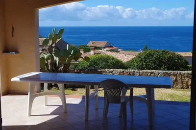 a blue table and chairs on a balcony with the ocean at villa marina in Sartène