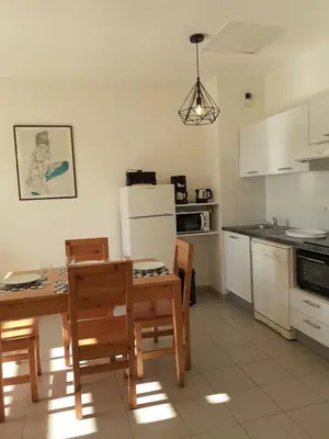 a kitchen with a table and chairs and a refrigerator at Bel appartement avec piscine- Poggio Mezzana in Poggio-Mezzana