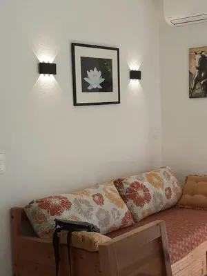 a living room with a couch and two lights on the wall at Bel appartement avec piscine- Poggio Mezzana in Poggio-Mezzana