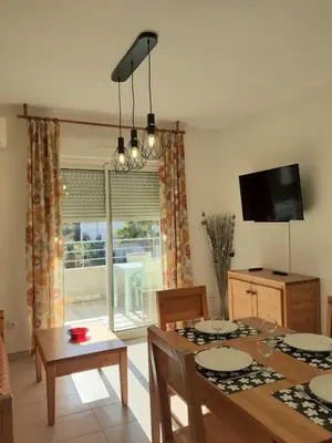 a living room with a dining room table and a television at Bel appartement avec piscine- Poggio Mezzana in Poggio-Mezzana