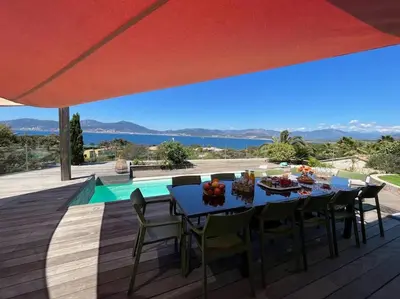 a table and chairs on a deck under a red umbrella at Luxury Villa with Stunning Panoramic Views in Grosseto-Prugna