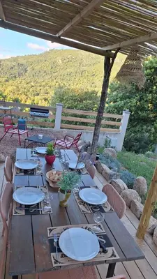 a wooden table with chairs and plates on it at VILLA I BAGHI - sans vis-à-vis au calme in Sainte-Lucie de Porto-Vecchio