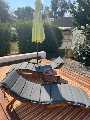 a table and an umbrella and chairs on a deck at Helles freundliche Ferienhaus für Naturisten FKK auf Korsika in Linguizzetta