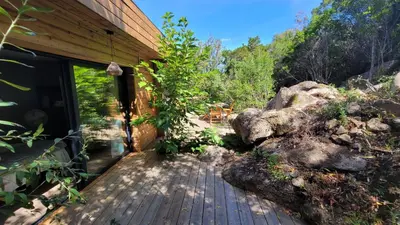 a wooden deck next to a house with a rock at A Dimora di Murza Liliekaena in Albitreccia