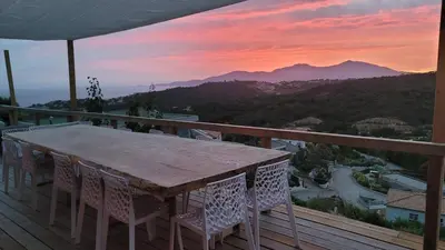 a table and chairs on a deck with a sunset at A Dimora di Murza Liliekaena in Albitreccia
