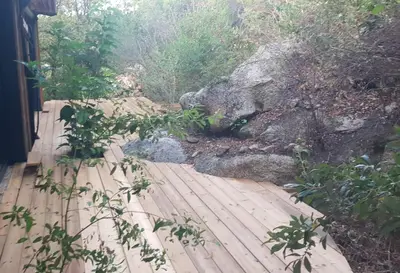 a wooden walkway next to a large rock at A Dimora di Murza Liliekaena in Albitreccia