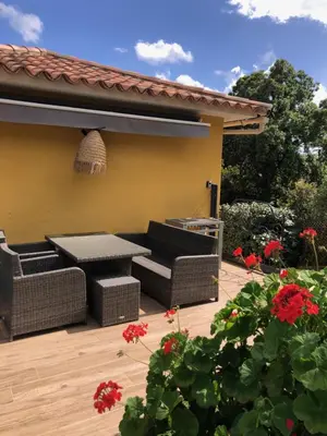 a patio with two wicker furniture and red flowers at Cap Martin. in Lecci