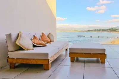 a couch with pillows on it next to the water at Le Galatée, T3 luxe in Porticcio