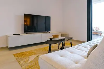 a living room with a white couch and a tv at Le Galatée, T3 luxe in Porticcio