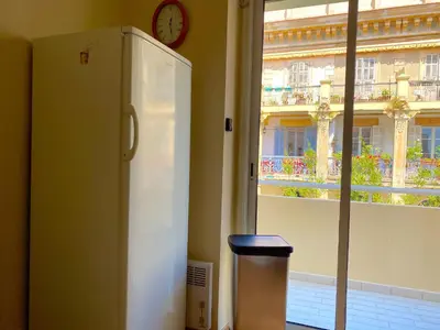 a white refrigerator next to a window with a clock at T3 Ajaccio Sacrée Coeur in Ajaccio