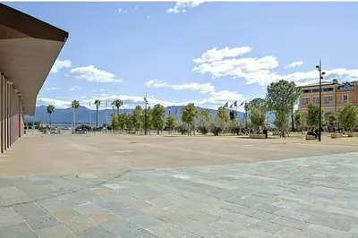 a large parking lot with palm trees and a building at Appartement Roi Jérôme - Hypercentre in Ajaccio