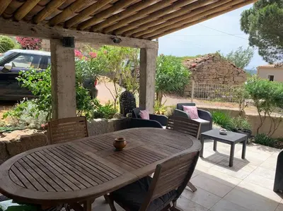a wooden table and chairs on a patio at Jolie maison individuelle dans l’extrême sud in Monacia-dʼAullène