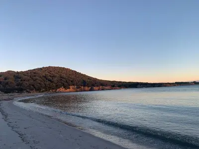 a beach with a hill in the distance and the ocean at Jolie maison individuelle dans l’extrême sud in Monacia-dʼAullène