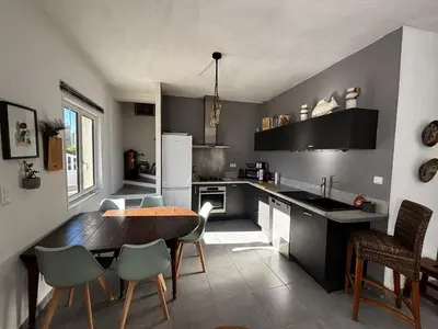 a kitchen with a table and chairs and a table and a kitchen with a refrigerator at Jolie maison individuelle dans l’extrême sud in Monacia-dʼAullène
