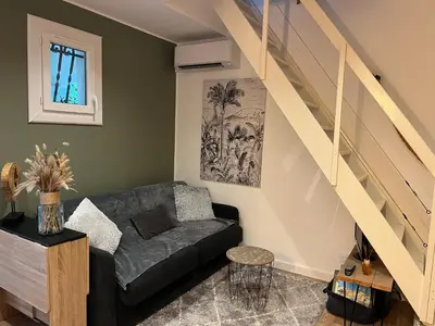 a living room with a couch and a staircase at Porticcio- Duplex dans propriété privée in Cauro