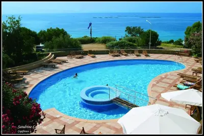 a large swimming pool with chairs and the ocean at Magnifique T2 vue Mer Sanguinaires in Ajaccio
