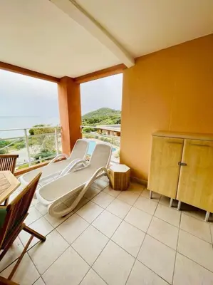 a waiting room with a white chair on a balcony at Magnifique T2 vue Mer Sanguinaires in Ajaccio