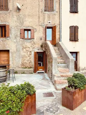 an old building with a staircase leading to a door at Charmant petit appartement place de l eglise in Piana
