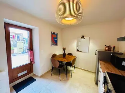 a dining room with a table and a chandelier at Charmant petit appartement place de l eglise in Piana
