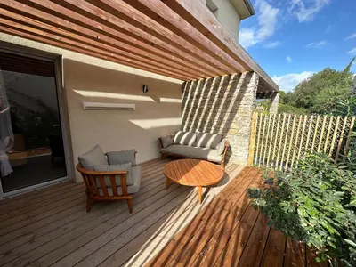a patio with a couch and a table on a deck at T4 Cala Rossa - 3 Ch - Piscine et Plage à pied in Lecci
