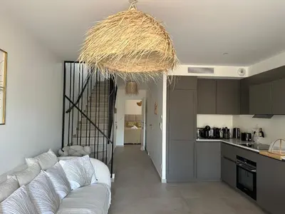 a living room with a couch and a kitchen at T4 Cala Rossa - 3 Ch - Piscine et Plage à pied in Lecci