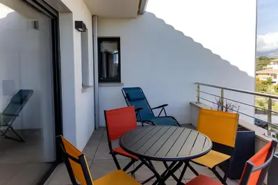 a patio with a table and chairs on a balcony at Domaine d'Arca - Gauguin 12 - 6 pers in Porto-Vecchio