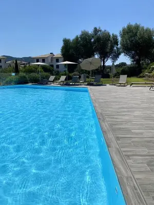 a blue swimming pool with chairs and umbrellas at Domaine d'Arca - Flaubert 06 - 6 pers in Porto-Vecchio