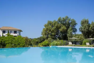 a large blue swimming pool with chairs and umbrellas at Domaine d'Arca - Flaubert 06 - 6 pers in Porto-Vecchio