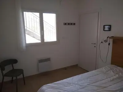 a bedroom with a bed and a window and a chair at Résidence front de mer + Piscine in Linguizzetta