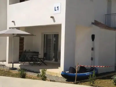 a blue kayak next to a building with an umbrella at Résidence front de mer + Piscine in Linguizzetta