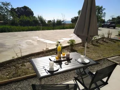 a picnic table with an umbrella and drinks on it at Résidence front de mer + Piscine in Linguizzetta