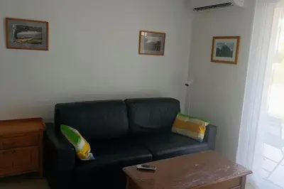 a living room with a black couch and a table at Résidence front de mer + Piscine in Linguizzetta