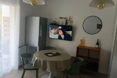 a living room with a table and a tv on the wall at Résidence front de mer + Piscine in Linguizzetta