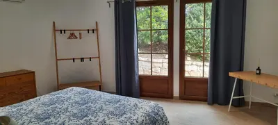 a bedroom with a bed and two large windows at RESIDENCE GIULIA in Propriano