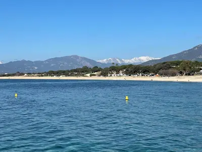 a body of water with yellow buoys in the water with a beach at U refuggiu in Porticcio