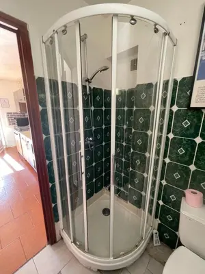 a shower in a bathroom with green tiles at U refuggiu in Porticcio