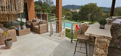 a patio with a table and chairs and a pool at villas-majos : Magnifique villa vue mer à 3 minutes des plages in Sainte-Lucie de Porto-Vecchio