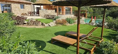 a yard with a chair and an umbrella at villas-majos : Magnifique villa vue mer à 3 minutes des plages in Sainte-Lucie de Porto-Vecchio