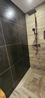 a shower in a bathroom with a large tile wall at villas-majos : Magnifique villa vue mer à 3 minutes des plages in Sainte-Lucie de Porto-Vecchio