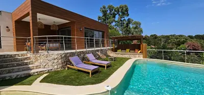 a house with a swimming pool and two purple chairs at villas-majos : Magnifique villa vue mer à 3 minutes des plages in Sainte-Lucie de Porto-Vecchio