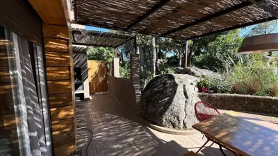 a patio with a table and a large rock at Villa A Liccia piscine 4pers proche Ville et Port in Porto-Vecchio