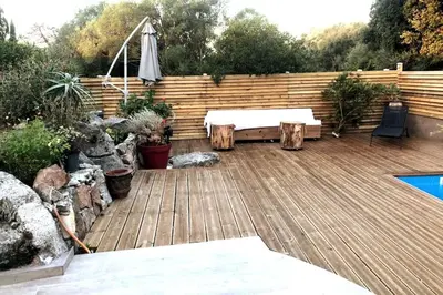 a wooden deck with a table and an umbrella at Villa A Liccia piscine 4pers proche Ville et Port in Porto-Vecchio