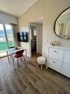 a living room with a table and a mirror at Appartement ensoleillé à Ajaccio in Ajaccio